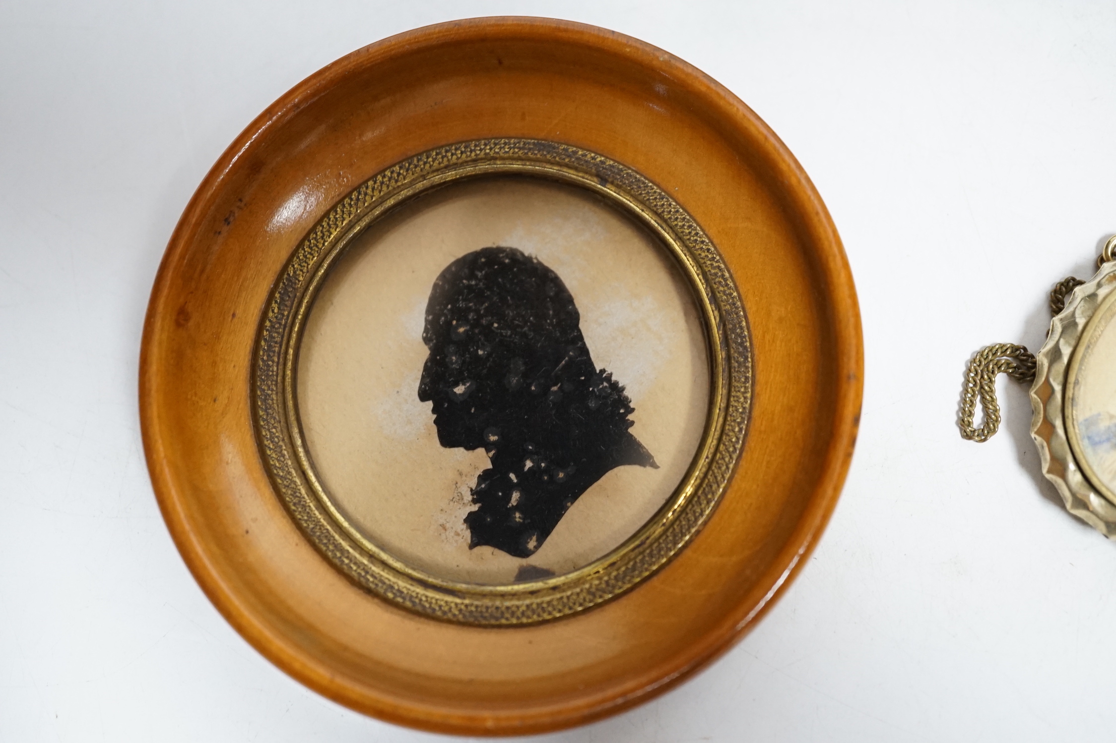 Three miniature reverse glass painted silhouettes, a relief plaque of the virgin and child and a watercolour portrait pendant